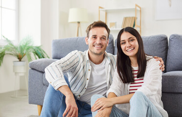 Obraz premium Joyful portrait of a happy family couple sitting and embracing on the floor in living room. They share a moment of love and bonding, radiating passion and happiness together at home.