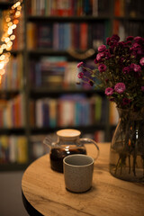 Cozy evening still life with flowers, teapot, cup of tea and copy space.