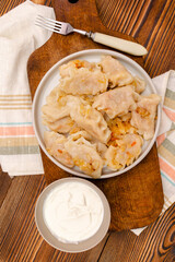 Homemade dumplings,vareniki,varenyky,pyrohy with stewed cabbage.Traditional ukrainian popular national dish,cuisine served with sour cream on gray background.