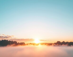 Obraz premium A serene sunrise emerges above a misty landscape, casting a warm glow over the horizon and creating a tranquil atmosphere.