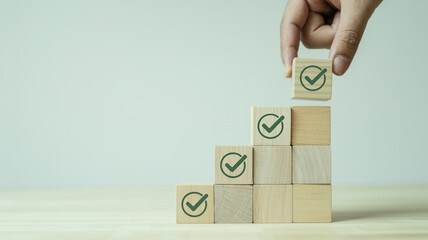 Wooden blocks with green checkmarks arranged in ascending steps progress