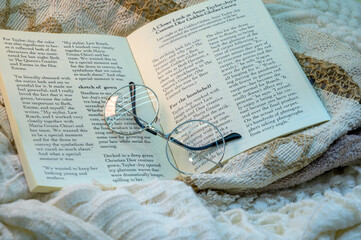 A pair of glass spectacles is placed on an open book.
