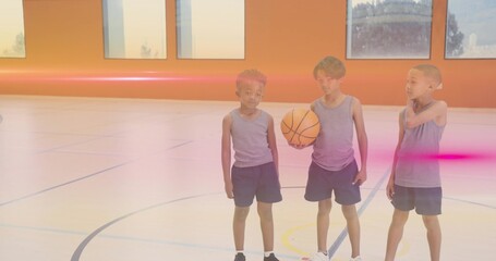 Standing three boys wearing matching grey sportswear at gym court, with basketball and court lines