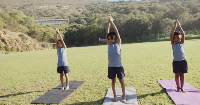 Fototapeta Three boys in sportswear practicing mountain pose on sports field, with yoga mats and goalposts