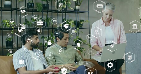 Three professionals reviewing printed charts on laptop in office lounge, with digital finance icons