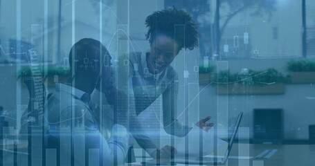 Colleagues in business attire analyzing market data at office desk, with laptop and charts overlay