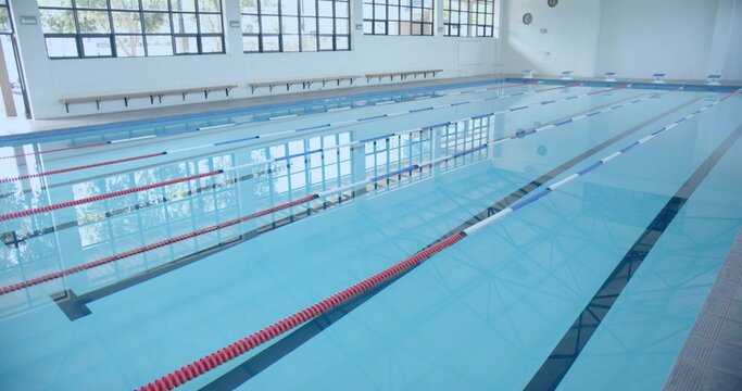 Fototapeta Empty lap pool occupying central pool hall, with red and blue lane dividers and wooden bench