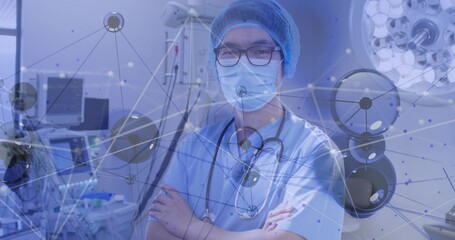 Standing Chinese doctor in scrubs in OR with stethoscope, monitor and pump under digital overlay © vectorfusionart