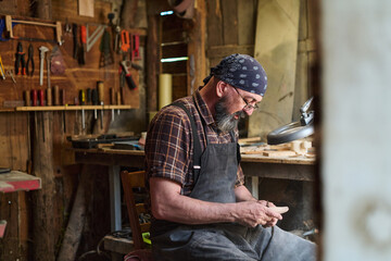 Craftsman working in his workshop, artisan shaping wood with hand tools, woodworking project, small business owner, hobbyist in rustic setting, creative process, skilled labor.