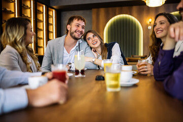 Couple hugging at restaurant with friends