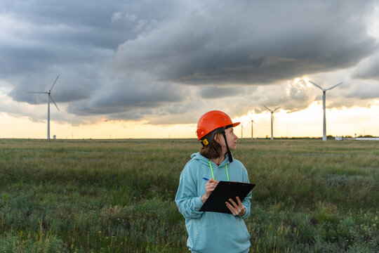 Woman surveying wind farm while wearing protective helmet