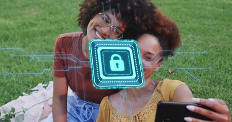 Friends framing selfie on lawn then swiping smartphone revealing padlock highlighting data security