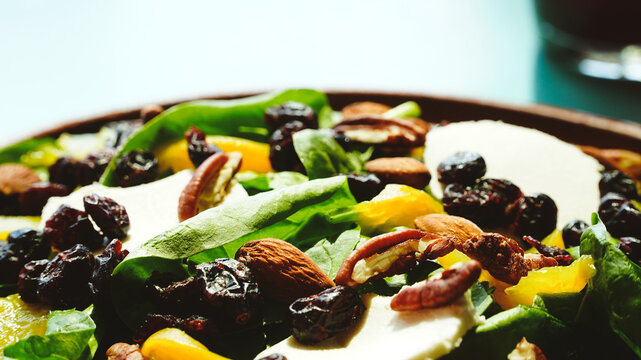 Ensalada fresca servida en un plato de barro, con mezcla de espinacas, aguacate, almendras, pasas y aderezo en una peque&ntilde;a cazuelita. Los tonos verdes y dorados contrastan con la mesa turquesa