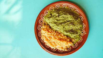 Platillo de pollo en salsa verde acompañado de arroz mexicano, servido en plato artesanal sobre...