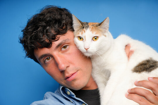 Young man with cat against a solid blue background
