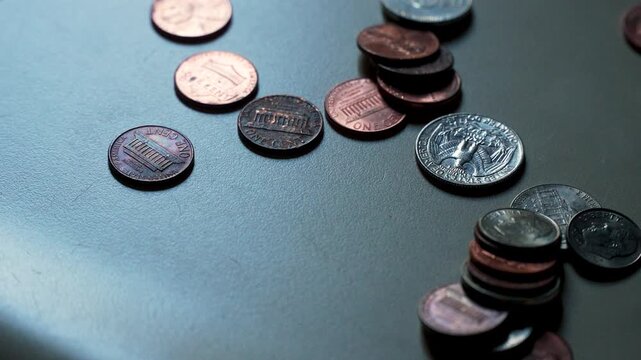 American coins and currency being tossed onto a countertop (slow motion)