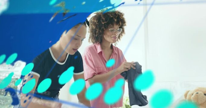 Two women approaching bed sorting laundry and making bed for neat room under technology overlay