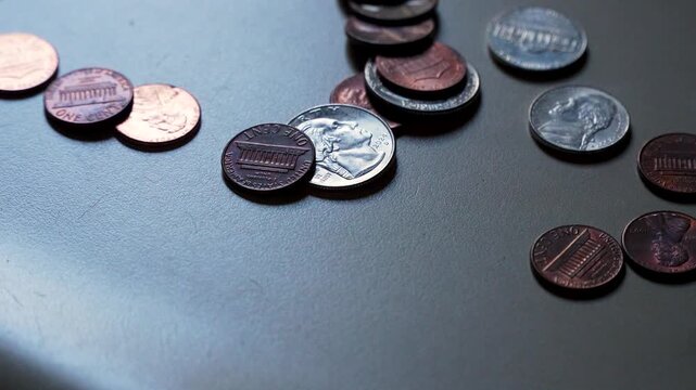 Close-up of American coins and currency being tossed onto a countertop (slow motion)