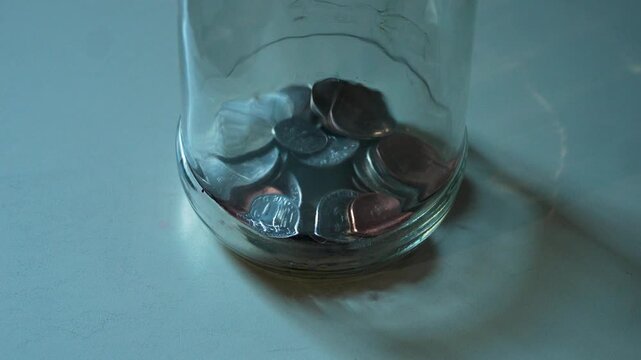 Coins falling into the bottom of a glass jar