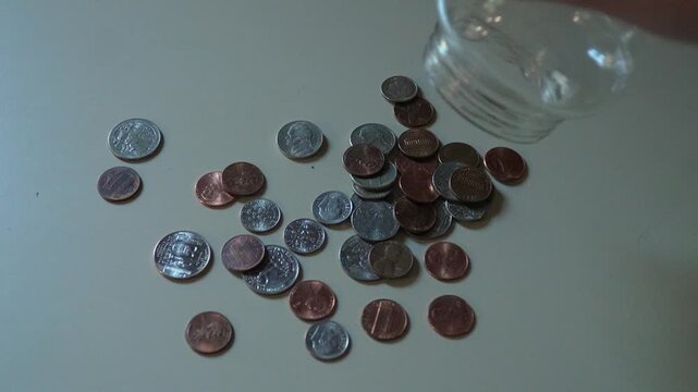 Coins falling out of a glass jar onto a countertop