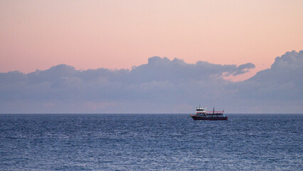 A nighttime boat cruise on a sightseeing boat. The ship glows against the sunset sky, with the last glimmers of sunlight reflecting off the water.