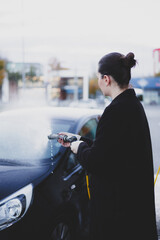 A lady at the car wash is washing her car.