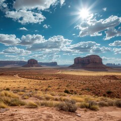 Vast desert panorama under brilliant sunlit skies showcases iconic sandstone buttes and arid landscape