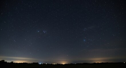 A vast, dark night sky filled with countless stars, with faint city lights on the horizon