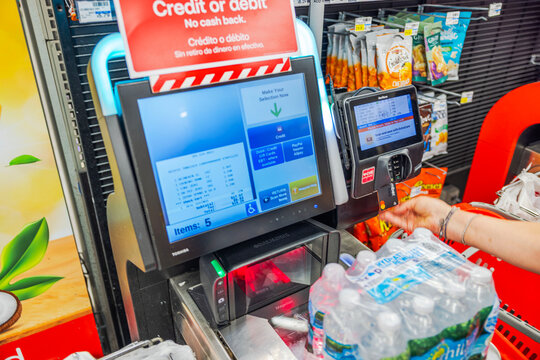 Close up view of woman inserting credit card into payment terminal at self checkout in CVC store background. Miami Beach. USA.