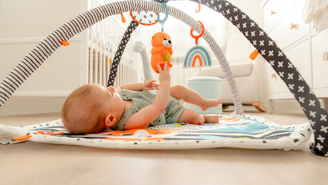 Infant playing with toy on a colorful playmat