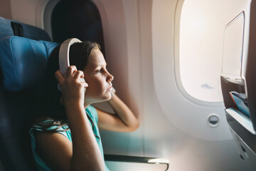 Girl wearing headphones sitting on airplane seat during flight