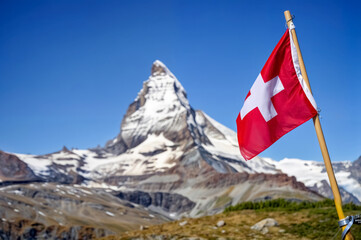 Majestic Matterhorn mountain with Swiss flag waving in clear blue sky during a sunny day