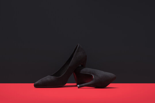 Black suede high heels on striking red background