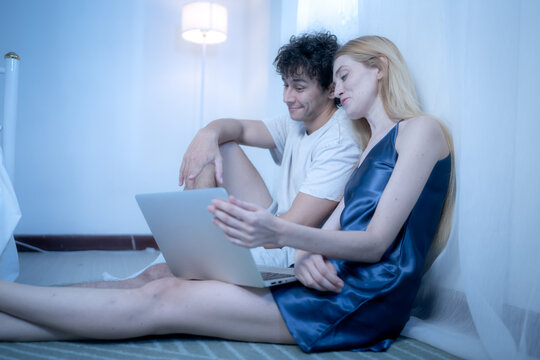 A couple relaxes before bed by browsing social media on a laptop