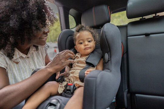 Mother securing child in car seat with care