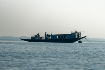A silhouette of a boat with fishermen on a calm lake