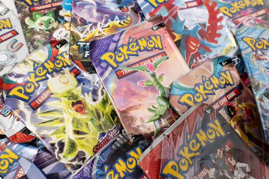 Bradford, UK Oct 30 2025 - A collection of vibrant metallic pok&eacute;mon trading card game booster packs arranged over each other.
