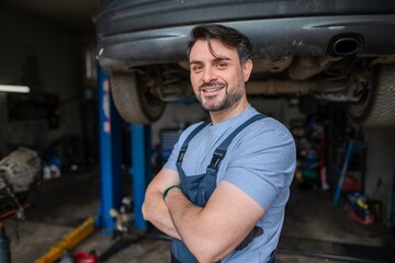 Confident mechanic smiling with arms crossed in his garage