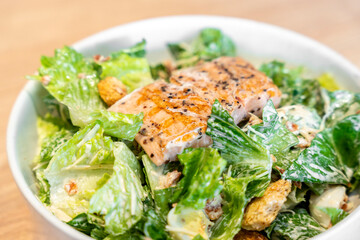 Vegetarian ceasar salad with grill steak salmon cherry tomatoes croutons and lettuce.