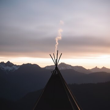 Smoke rising from a tipi against a mountainous sunset background  native american Heritage Day