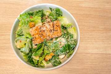 Top view of vegetarian ceasar salad with grill steak salmon cherry tomatoes croutons and lettuce.