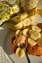 French toasts with banana slıces and spoon with peanut butter on whıte plate top vıew