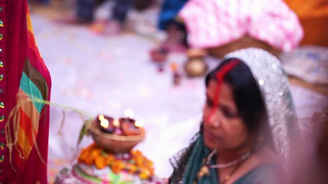 Close-up of woman giving offerings during Chhath Puja, holding soop with fruits and diyas in soft morning light.