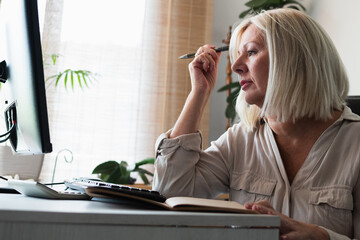 Senior woman concentrating, working from home office