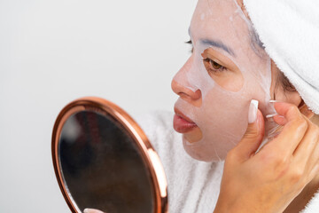 Woman applying hydrating sheet mask during beauty routine