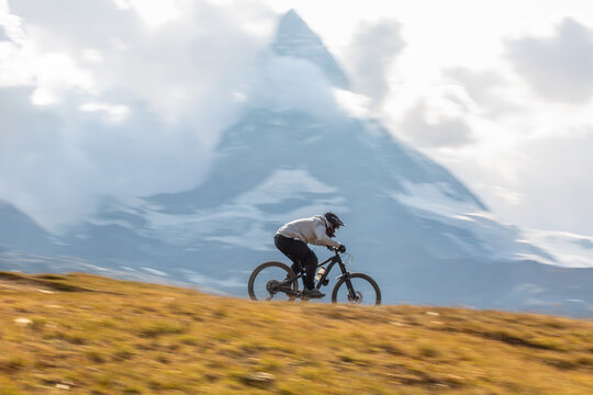 Cyclist riding downhill in Zermatt&rsquo;s mountainous terrain