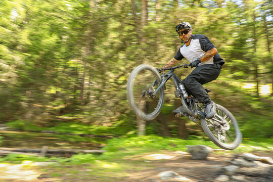 Mountain biker jumping on forest trail in Zermatt