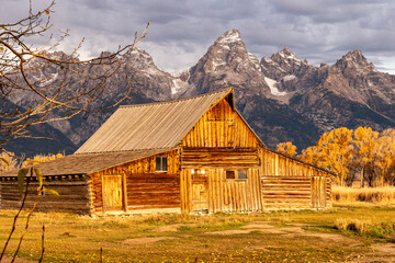 One of the iconic Moulton barn in Grand Teton National Park at Sunrise with Grand Teton and the snowcapped mountains of the Teton Range behind the field at golden hour