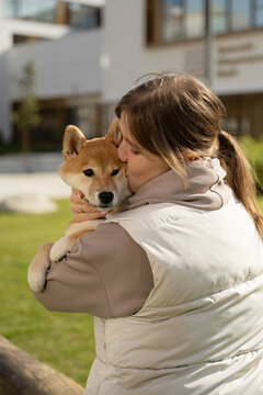 Woman cuddling shiba inu puppy outdoors in