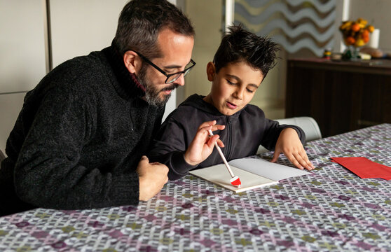 Father and child writing holiday letters together